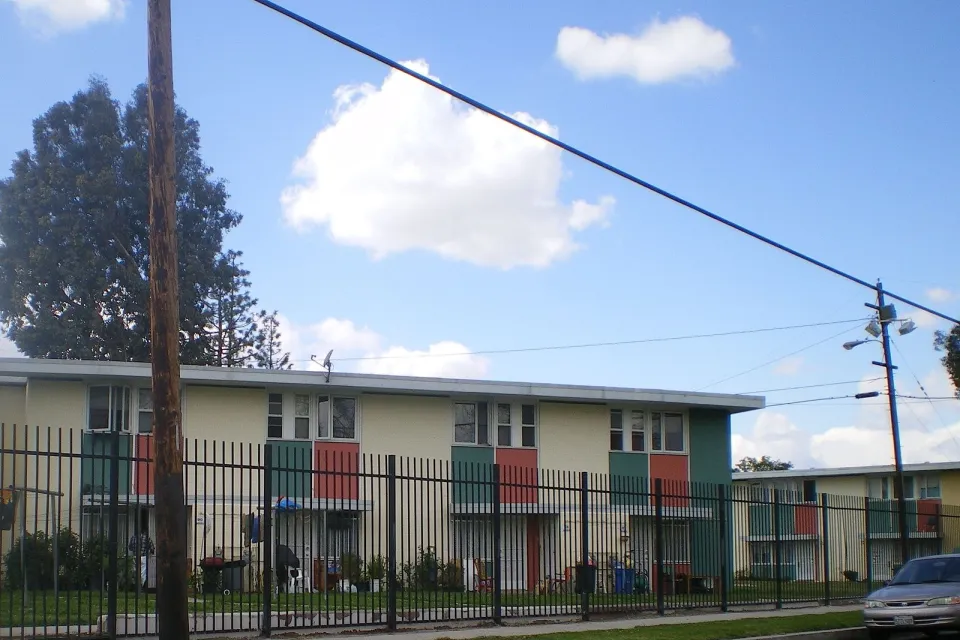 Two-story apartment building behind black iron fence in Pacoima, California